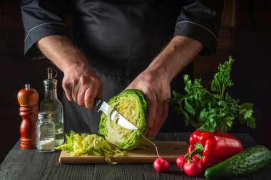 Profesyonel aşçı, lahanayı bıçakla kesiyor. Restoranın mutfağında sebze salatası pişiriyorum.