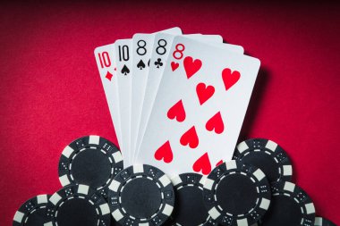 Kazanan poker kombinasyonu full house ya da full boat. Poker kulübünde fişler ve kartlar kırmızı masada.