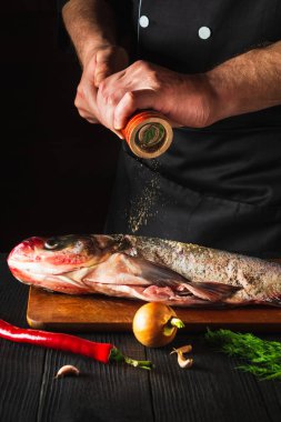 Aşçı taze balık kocakafalı sazan balığı serpiştiriyor. Balık yemi pişirmeye hazırlanıyorum. Restoranda ya da kafe mutfağında çalışma ortamı