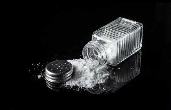 黑色背景上的盐瓶里有大量的盐 过量摄入盐的概念 可能是糖尿病或其他疾病的原因 — 图库照片
