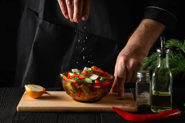 厨师把新鲜蔬菜沙拉撒在木制桌子上的盘子里 在餐馆的厨房里烹调健康食品 — 图库照片