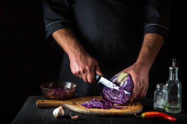 Aşçı bir bıçakla kırmızı lahana kesiyor. Restoranın mutfağında sebze salatası pişiriyorum. Sebze diyeti fikri