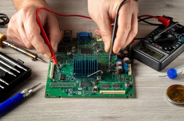 Bilgisayar ya da elektronik onarım. Usta testçi, servis atölyesindeki elektronik panoyu kontrol ediyor.