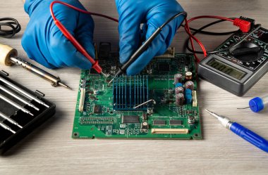 Bilgisayar ya da elektronik onarım. Usta testçi, servis atölyesindeki elektronik panoyu kontrol ediyor.