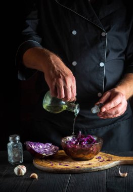 Aşçı taze lahana salatasına zeytinyağı döker. Lokanta mutfağında sağlıklı yemekler pişirmek..