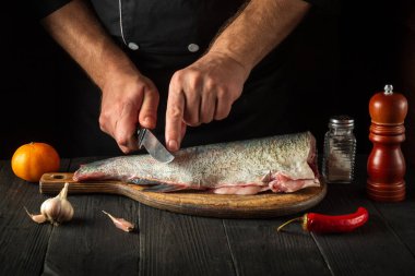 Şef pişirmeden önce balığı keser. Restoranın mutfağında çalışma ortamı. Balık diyeti konsepti.