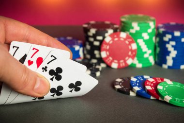 Poker kartları. Üçlü ya da set kombinasyonlu. Kumarbazın eli poker kulübünde kağıt oynar.