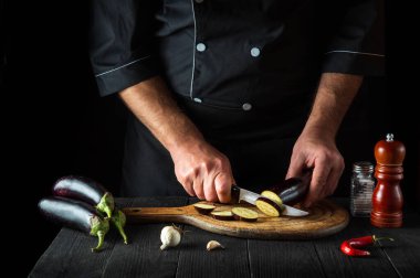 Profesyonel şef restoranın mutfağında patlıcan kesiyor. İş sırasında aşçının ellerini yakın plan çek. Lezzetli kahvaltı ya da akşam yemeği.