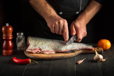 Aşçı pişirmeden önce balığı keser. Restoranın mutfağında çalışma ortamı. Balık diyeti konsepti