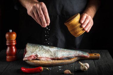 Aşçı taze balık serpiştirir. Şef balık yemi için hazırlanıyorum. Restoranın mutfağında çalışma ortamı