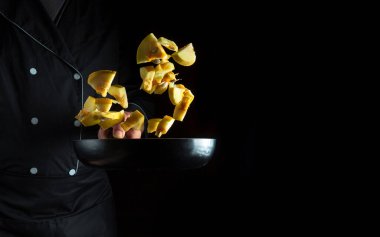 Aşçı bir tavada kabak hazırlar. Sebze pişirmek sağlıklı vejetaryen yemekleri ve siyah arka planda yemek.