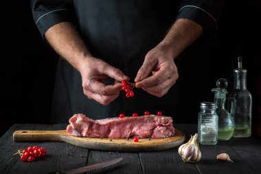 Şef çiğ dana eti hazırlar. Pişirmeden önce, aşçı bifteğe viburum koyar. Ulusal yemek restoranın mutfağında hazırlanıyor..