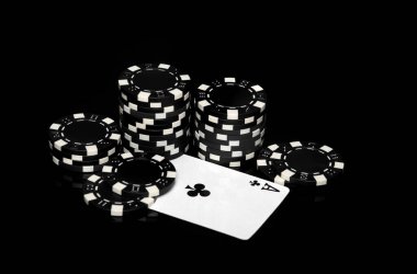 Kumarhanedeki siyah masada çipler ve as haç. Pokerde servet ya da başarı.
