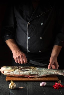 Profesyonel şef, restoranın mutfağında gümüş sazan balığı hazırlıyor. Bıçakla balık kesmeye hazırlık. Mutfak masasında çalışma ortamı.