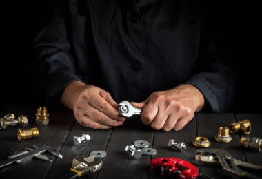 Tesisatçı somunu ingiliz anahtarıyla sıkıyor. Atölyedeki çalışma ortamına yakın çekim. Gaz ekipmanı kurulumu