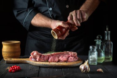 Profesyonel şef çiğ et hazırlar. Pişirmeden önce, şef bifteğe biber ekler. Ulusal yemek restoranın mutfağında hazırlanıyor..