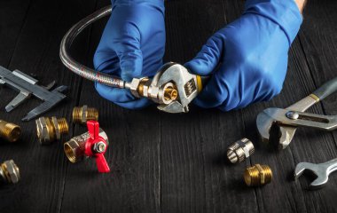 Profesyonel tesisatçı, yüksek basınçlı hortumu pirinç tesisatına bir ingiliz anahtarıyla bağlıyor. Gaz kurulumu sırasında atölyede çalışma ortamı.