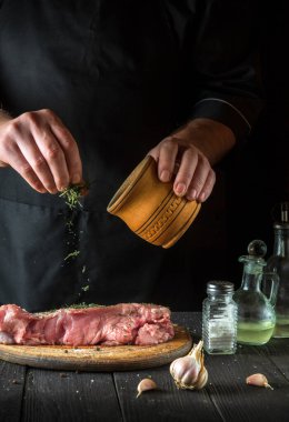 Aşçı çiğ dana eti hazırlar. Pişirmeden önce, şef bifteğe kuru bir bitkisel baharat ekler. Ulusal yemek restoranın mutfağında hazırlanıyor.