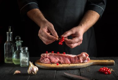 Profesyonel şef çiğ et hazırlar. Pişirme aşçısı bifteğe viburum koymadan önce. Ulusal yemek restoranın mutfağında hazırlanıyor.