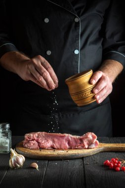 Profesyonel aşçı çiğ et hazırlar. Aşçıbaşı bifteğe tuz eklemeden önce. Ulusal yemek restoranın mutfağında hazırlanıyor.