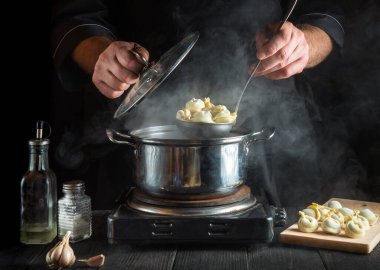 Profesyonel aşçı mutfakta bir tencerede pelmeni hazırlar. Çalışırken şefin ellerini yakın plan çek. Lezzetli bir öğle yemeği ya da kahvaltı hazırlama fikri