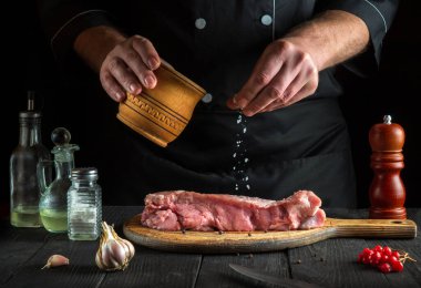 Aşçı çiğ dana eti hazırlar. Aşçı pişirmeden önce bifteğe tuz ekler. Ulusal yemek mutfakta hazırlanıyor.