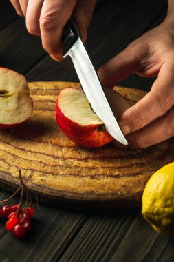 Aşçı komposto veya meyve suyu yapmak için elmaları kesme tahtasıyla keser. Bir dizi vitamin için elma diyeti. Mutfak masasında çalışma ortamı.