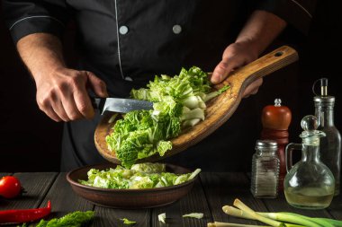 Şef taze Napa lahana salatası yapar. Restoranın mutfağında dilimleme hazırlığı. Sebze diyeti fikri.