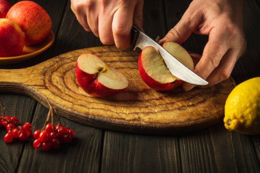 Aşçı komposto veya meyve suyu yapmak için elmaları kesme tahtasıyla keser. Bir dizi vitamin için elma diyeti. Mutfak masasında çalışma ortamı.