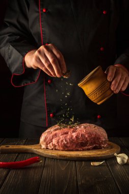 Çiğ etle lezzetli ulusal yemekler pişirmek. Restoran ya da otel için et tarifi. Şef kuru baharat ekliyor.