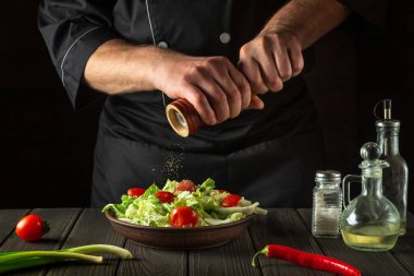 Aşçı bir restorandaki taze sebze salatasına biber ekler. Bir değirmeni tutan şeflerin yakın çekimi. Sağlıklı ve lezzetli yemekler pişirmek..