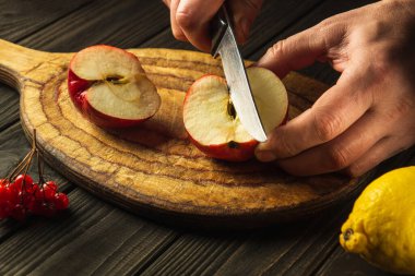 Şef komposto veya meyve suyu yapmak için elmaları kesme tahtasıyla keser. Bir dizi vitamin için elma diyeti. Mutfak masasında çalışma ortamı