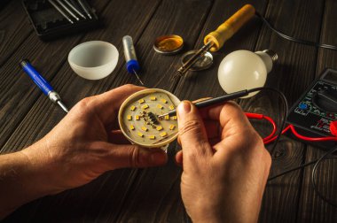 Evde ampul tamiri için testçi ya da servis kullanılıyor. Atölyedeki ustanın elleri.