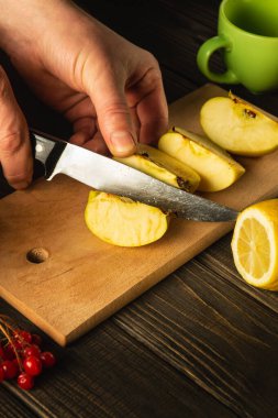 Evde elma reçeli yapıyorum. Bıçaklı bir aşçının elleri kesme tahtasındaki taze elmaları kesiyor. Bir dizi vitamin için meyve diyeti.