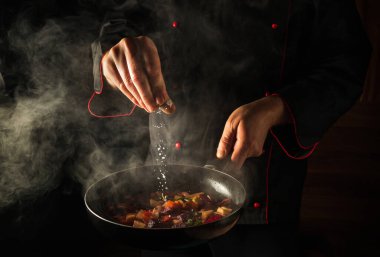 Taze sebze pişiriyorum. Şef sıcak tavaya tuz ekliyor. Reklam alanı olan bir otel için moleküler mutfak menüsü fikri.