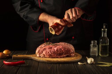 Çiğ etle lezzetli ulusal yemekler pişirmek. Restoran ya da otel için et tarifi. Şef biber ekliyor..