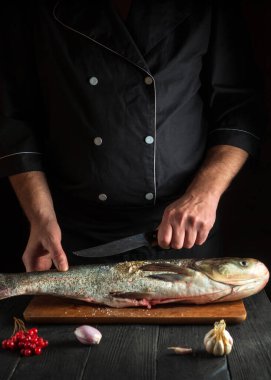 Şef restoranın mutfağında gümüş sazan balığı hazırlıyor. Bıçakla balık kesmeye hazırlık. Avrupa mutfağı