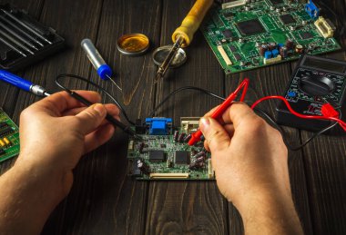 Elektronik ekipman onarım servisi. Elektronik panoların tamiri. Demir lehimleme ustası atölyede ekipman tamir eder.