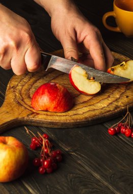 Şef komposto veya meyve suyu yapmak için bir bıçakla elmaları kesme tahtasıyla keser. Bir dizi vitamin için elma diyeti. Mutfak masasında çalışma ortamı
