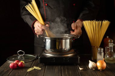 Öğle yemeği için lezzetli çorba pişiriyorum. Mutfakta çalışma ortamı. Şef tencerede spagetti pişiriyor. Moleküler gastronomi
