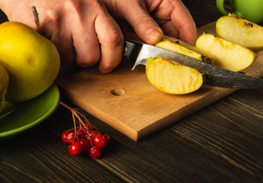 Şef komposto veya meyve suyu yapmak için elmaları kesme tahtasıyla keser. Bir dizi vitamin için elma diyeti. Mutfak masasında çalışma ortamı.