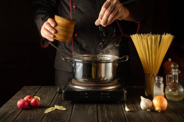 Akşam yemeği hazırlarken spagetti çorbası tuzlanmalıdır. Mutfakta yemek pişirirken. Büyük mutfak..