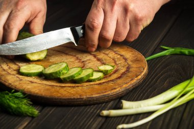 Mutfakta yeşil salatalık kesen şef. Taze sebzelerle lezzetli bir salata yapıyorum. Vejetaryen mutfağı