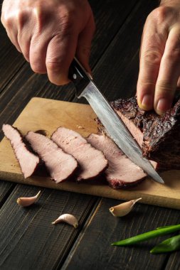 Şefin elleriyle akşam yemeği hazırlamadan önce fırında et dilimliyorum. Üst görüş aşçılık süreci konsepti. Köylü yemekleri.