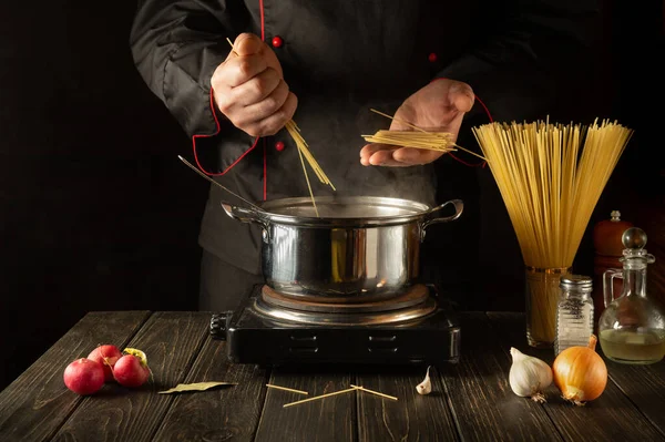 Profesyonel bir şef İtalyan makarnası hazırlar. Aşçı mutfakta spagetti tutuyor. Avrupa mutfağı