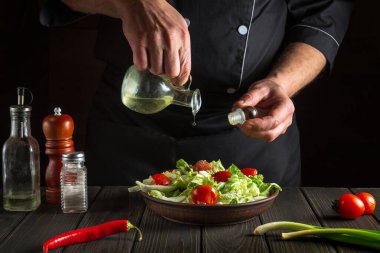 Profesyonel şef bir kase salataya zeytinyağı döker. Lezzetli ve sağlıklı yiyecekler ve vitaminler.