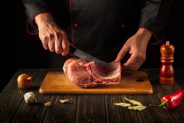 Çiğ kaburgalar küçük parçalara ayrılmalı. Mutfakta bıçaklı bir kasap elleri. Otel için lezzetli yemekler pişiriyorum..