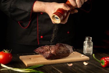 Şef fırınlanmış sığır etine biber serper. Mutfak masasında çalışma ortamı. Asya mutfağı.