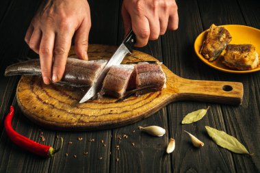 Bıçaklı şef tahta kesme tahtasına taze Merluccius balığı kesti. Eşsiz bir tarifle ulusal bir balık yemeğinin ev yemeği.