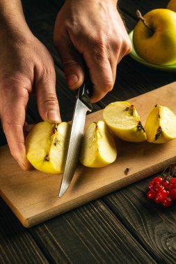 Aşçı komposto veya meyve suyu yapmak için elmaları kesme tahtasıyla keser. Bir dizi vitamin için elma diyeti. Mutfak masasında çalışma ortamı